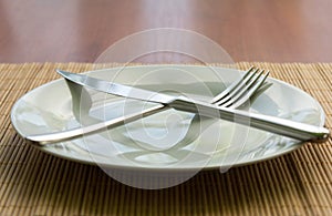 White empty plate, fork and knife on the table photo