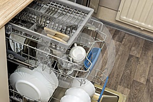 Clean dishes, cups, spoons and forks in a dishwasher at home kitchen