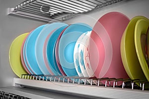 Clean dishes drying on metal racks for dishes on the shelves. Storing clean kitchen utensils and drying them