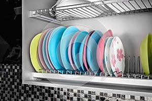 Clean dishes drying on metal racks for dishes on the shelves. Storing clean kitchen utensils and drying them