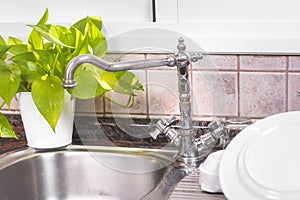 The Clean dishes are drying, on rustic kitchen metal sink.