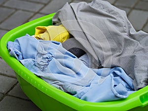 Clean dried clothes laying in a green laundry basket outdoors