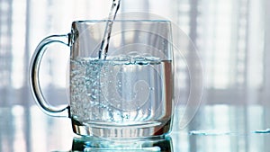 Clean drinking water being poured into a cup. Slow motion.