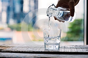 Clean drinking water is poured from a jug into a round glass cup