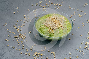 Clean eating and detox concept. Green vegan smoothie in bowl. Sprouted seeds around. Healthy green organic raw dish for