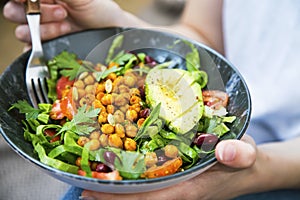 Clean eating, vegan healthy salad bowl closeup , woman holding salad bowl, plant based healthy diet with greens, chickpeas and