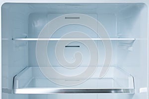 Clean empty shelves in white refrigerator. Empty open fridge with shelves, refrigerator. shelves in empty open white fridge