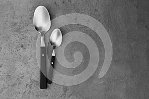 Clean empty table spoons on grey background. Space for text