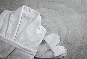 Clean folded bathrobe and slippers on stone background, flat lay
