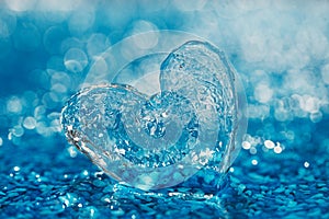 Clean glass heart on blue beach with water droplets