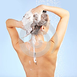 Clean hair, dont care. a young woman washing her hair in the shower against a blue background.