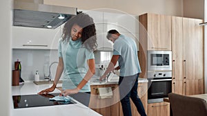 Clean Home. Two young professional cleaners in uniform working together in the kitchen. Happy afro american woman