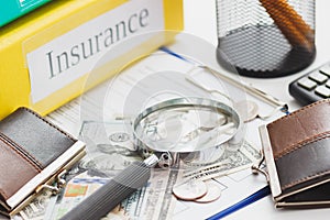 Clean insurance form, folders, magnifying glass, wallets and money