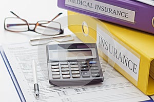 Clean insurance form, folders, pen, glasses and calculator