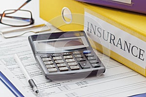 Clean insurance form, folders, pen, glasses and calculator