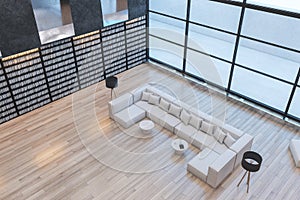 Clean library interior with tall bookshelves, panoramic windows, lounge area and wooden flooring.