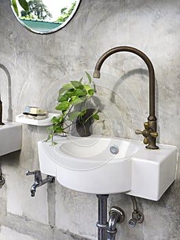 Clean loft style bathroom interior with white modern sink basin and brass faucet.