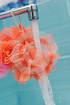 Clean loofahs hanging from a bathroom spigot