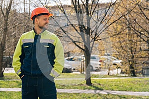 Clean male builder looks away. A man in special clothes and a helmet shows stands