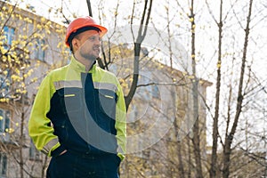 Clean male builder looks away. A man in special clothes and a helmet shows stands