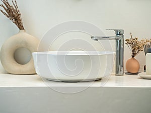 Clean minimal style powder room or bathroom interior with modern round sink basin, faucet, green leaves in modern design pots on.