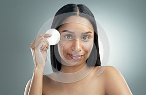 Clean, moisturise, repeat. a beautiful young woman holding a cotton pad against her face. photo