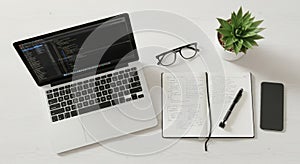 Overhead view of a laptop notebook glasses and plant on a desk