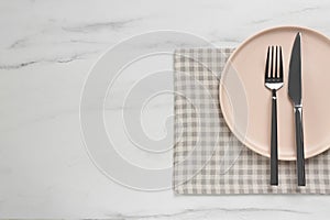 Clean plate with shiny silver cutlery on white marble table, flat lay. Space for text