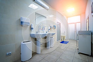 Clean public hospital bathroom with handrail soap and paper towel dispenser