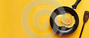 Clean and ready for cooking, an empty black nonstick skillet lies against a vibrant yellow background, epitomizing