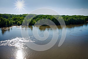 Clean river in summer, currents and whirlpools, green forest and meadow