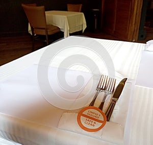 Clean and safe eating cutlery, disinfected and sanitized on table with white tablecloth, new normal in restaurant