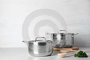Clean saucepans and spoons on table against light background. photo