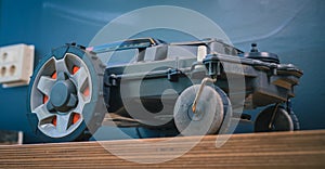 Clean side view of robotic lawnmower, motorized lawnmower being serviced on a table after a year of use in the mud and grass.