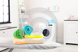 Clean soft towels on ironing board in laundry room