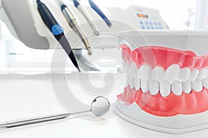 Clean teeth dental jaw model, mirror and dentistry instruments in dentist's office. photo
