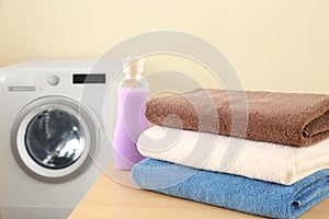 Clean towels and bottle of detergent on table in laundry room