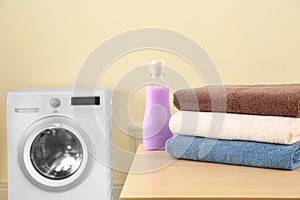 Clean towels and bottle of detergent on table in laundry. Space for text