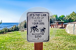 Clean Up After Your Dog sign against green grass and sky in San Diego California