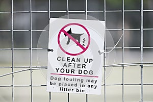 Clean up after your dog sign on fence promoting use of litter bin
