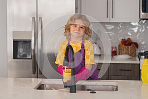 Clean washed dishes, dishwashing liquid with foam. Child helper housekeeping. Little boy sweeping and cleaning dishes at