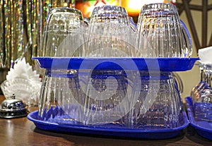 Clean, washed, glass transparent mugs for beer and wine glasses for wine, stand in groups on plastic blue trays, on  wooden bar