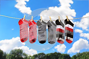 Clean washed striped socks hanging on clothesline to dry outdoors on sunny summer day. Clothesline with colored socks
