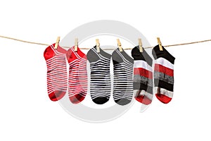 Clean washed striped socks hanging on rope isolated on white background. Clothesline with red, grey and white socks