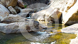 Clean water flow in rocky river in mountain close up. Rapid water stream from tropical waterfall pouring in mountain