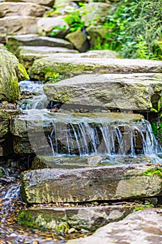 Clean water flowing between rocks of small waterfall