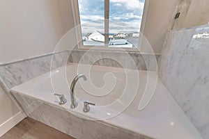 Clean white built in bathtub of home with view of neighborhood houses