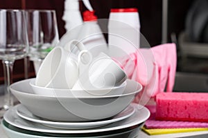 Clean white dishes, kitchen sponges and detergents on the table in the kitchen. Close-up. Selective focus