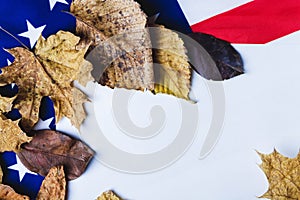Clean white sheet of paper on background of american flag with dry yellow leaves along edge.