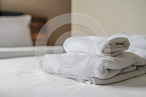 Clean white towels are folded beside bed to be ready for customers to use when it`s time to take shower because towels are